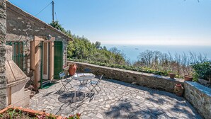 A stone building with a patio featuring a table and chairs, overlooking a coastal view. - Awesome home in La Spezia with WiFi (La Spezia)