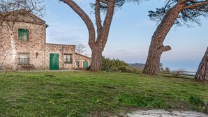 A stone building with a green door and windows, surrounded by grass and trees. - Awesome home in La Spezia with WiFi (La Spezia)
