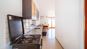A kitchen with a stove, cabinets, and a dining area with a table and chairs. - Nice apartment in Nevidane with house sea view (Nevidane)