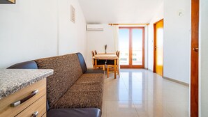 A modern living room with a sofa, a dining table with chairs, and a kitchen area with a countertop. - Nice apartment in Nevidane with house sea view (Nevidane)