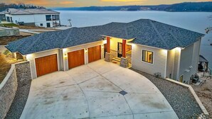 A two-story house with a garage, a stone retaining wall, and a view of a lake.