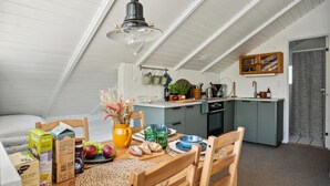 Ett mysigt kök på vinden med en matplats, inrett med ett träbord, stolar och ett urval av köksredskap och köksmaskiner.
