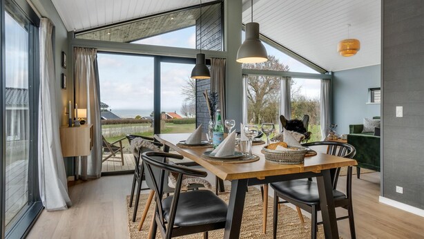 Een eetgedeelte met uitzicht op zee, een gedekte tafel voor twee personen, en een kat zittend aan tafel.