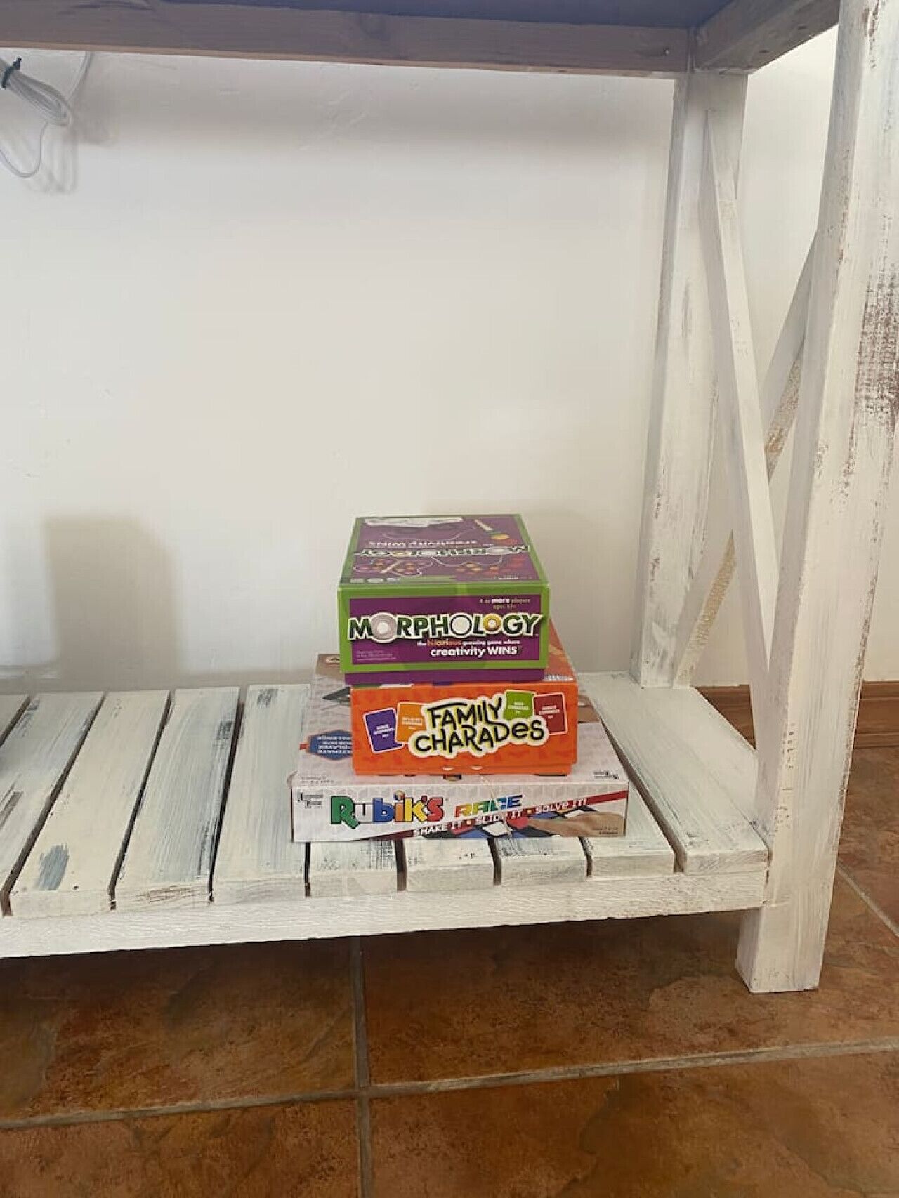 Une table en bois blanche sur laquelle sont empilés trois jeux de société.