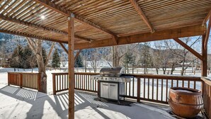 Ein überdachter Außenbereich mit Grill und großem Topf, umgeben von schneebedecktem Boden und Bäumen.