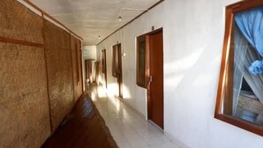 A long hallway with wooden flooring and white walls, leading to multiple doors. - Santai Warung Bali (Pecatu)