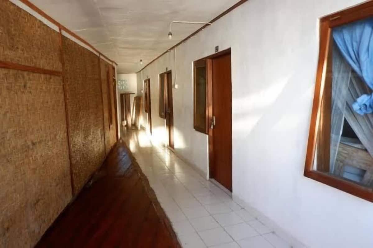 A long hallway with wooden flooring and white walls, leading to multiple doors.