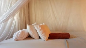 A bed with white bedding, two white pillows, and a red blanket. - Santai Warung Bali (Pecatu)