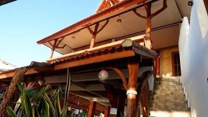 A building with a tiled roof, wooden beams, and a staircase leading to a door. - Santai Warung Bali (Pecatu)