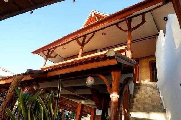 A building with a tiled roof, wooden beams, and a staircase leading to a door.