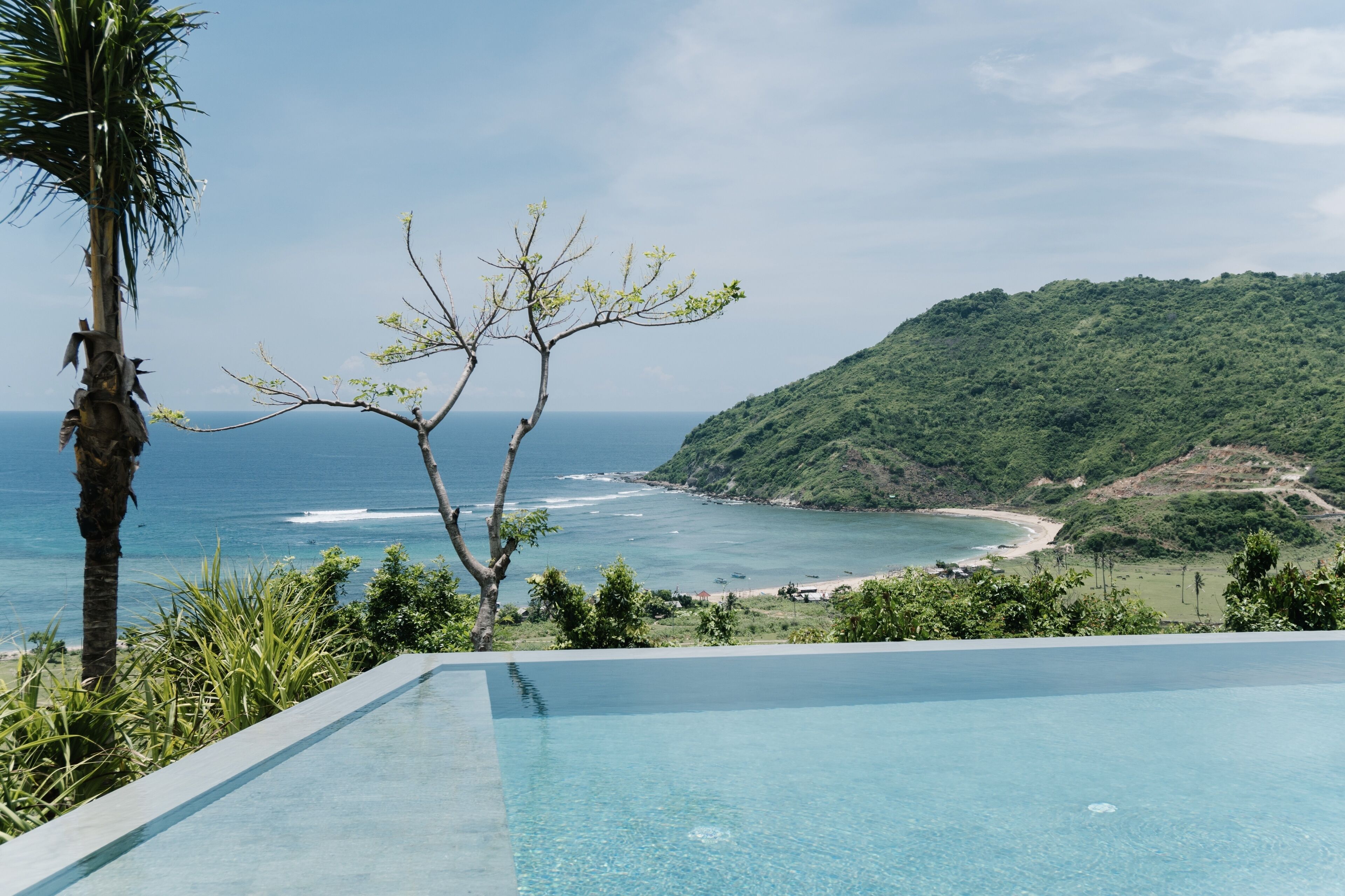 A clear view of a swimming pool with a view of the ocean and a beach.