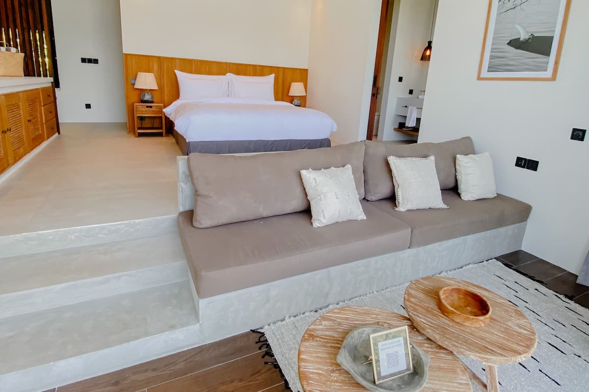 Ein modernes Hotelzimmer mit einem großen Bett, einer Sitzecke, einer kleinen Essecke und einer Treppe zu einem weiteren Raum.