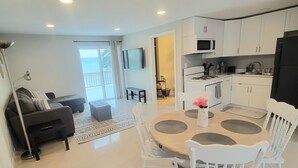 Una cocina moderna con armarios blancos, un refrigerador negro y un microondas.