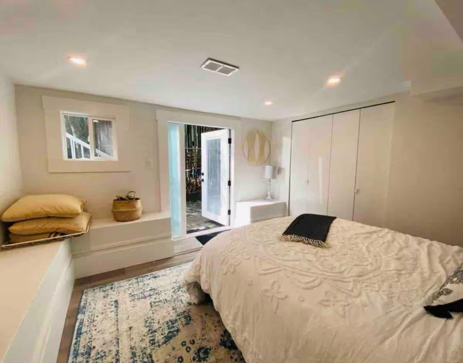 A bedroom with a bed, a nightstand, a window, a door, and a wardrobe.