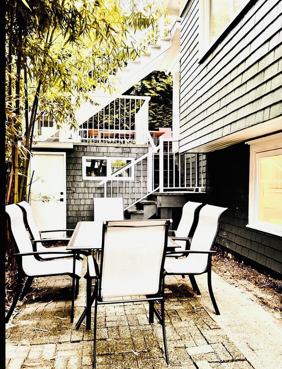 A patio with a table and chairs, a small staircase, and a building with a dark exterior.