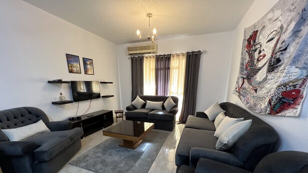 A modern living room with a sofa set, a coffee table, a flat-screen TV, and decorative wall art. - Luxury apartment new cairo alrehab (Cairo Governorate)
