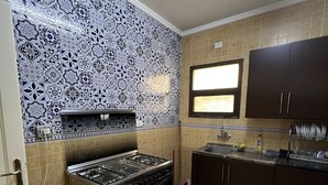 A kitchen with a gas stove, oven, and dark cabinets. - Luxury apartment new cairo alrehab (Cairo Governorate)