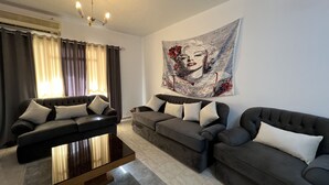 A living room with two sofas, a coffee table, and a large tapestry on the wall. - Luxury apartment new cairo alrehab (Cairo Governorate)