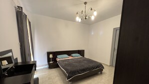 A bedroom with a bed, a nightstand, a lamp, a dresser, and a mirror. - Luxury apartment new cairo alrehab (Cairo Governorate)