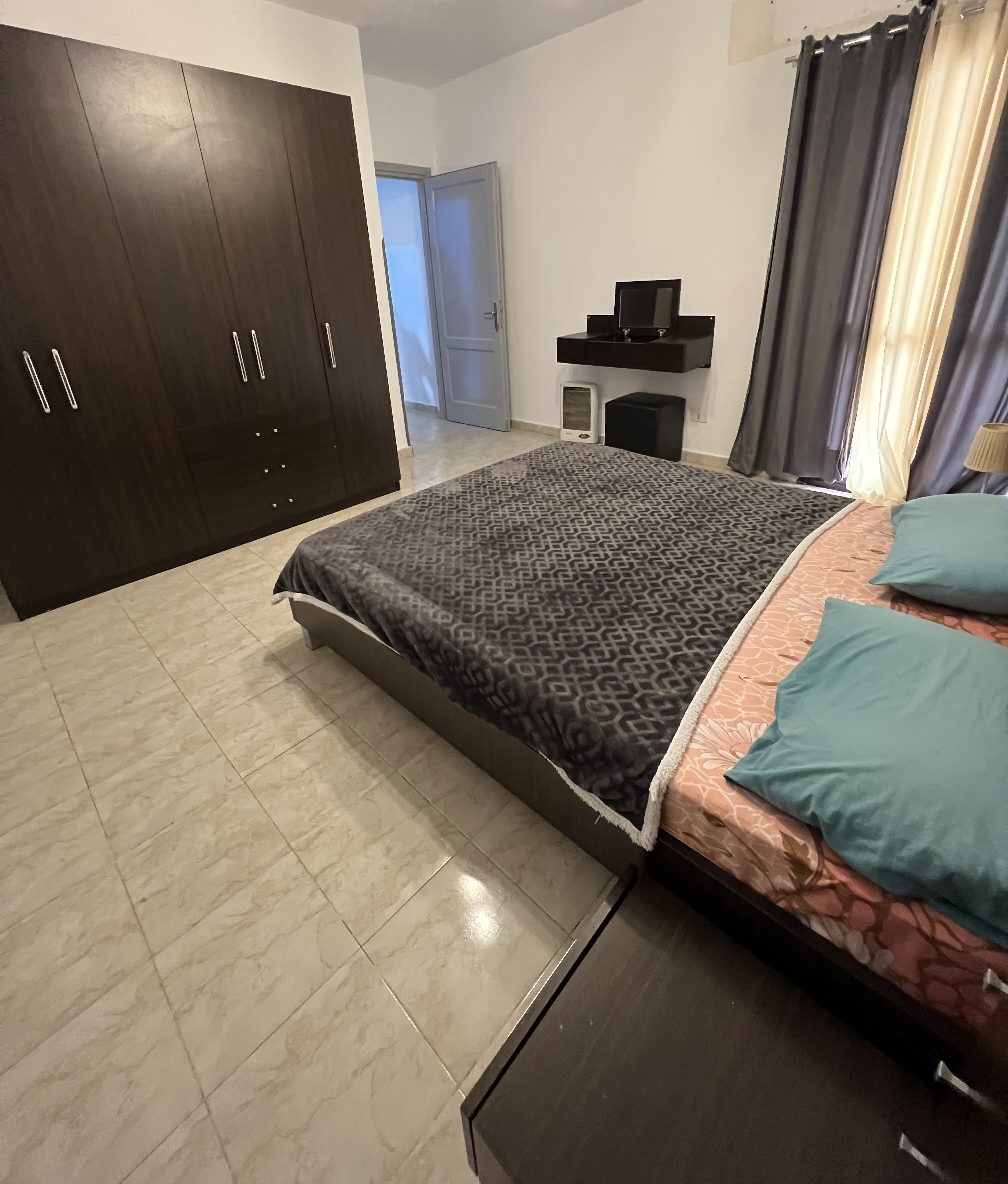 Una camera da letto con un letto, un armadio, un comodino e una porta che dà su un'altra stanza.