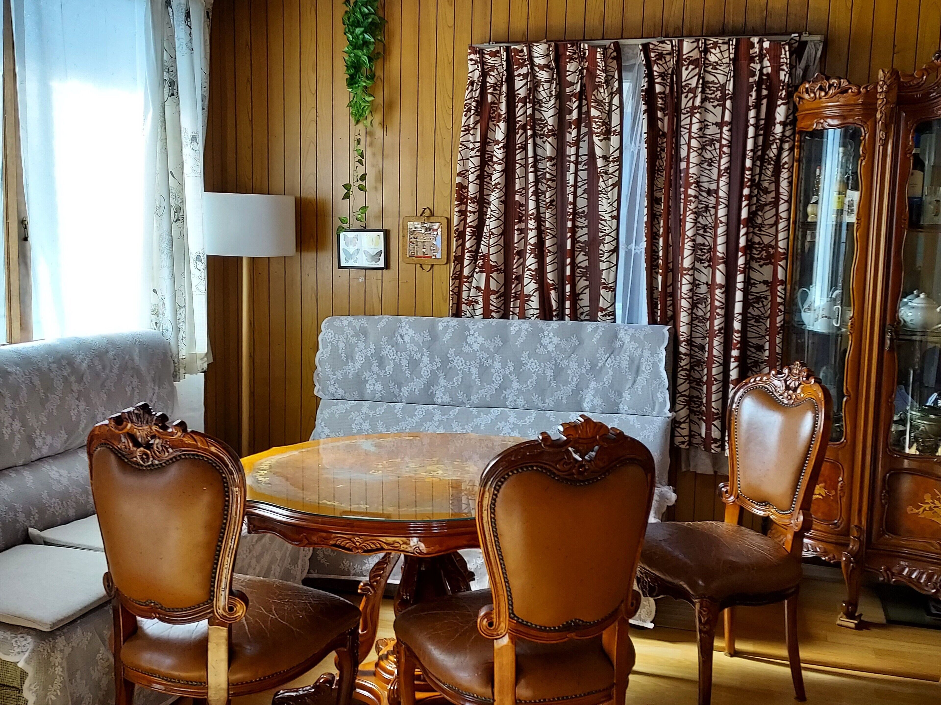 A living room with a sofa, a round table, and two chairs. There is a cabinet with glass doors and a lamp.