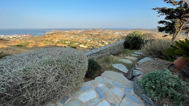 Un sentier de pierres mène à un belvédère offrant une vue panoramique sur une ville côtière et la mer.