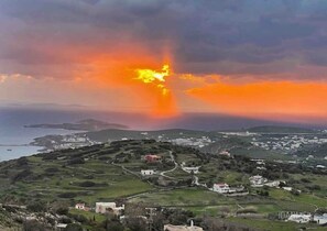 A coastal landscape with a sunset, buildings, and a winding road.