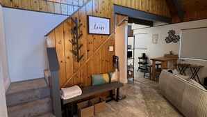Un interior acollidor i rústic amb una escala de fusta, una panxa i un sofà.