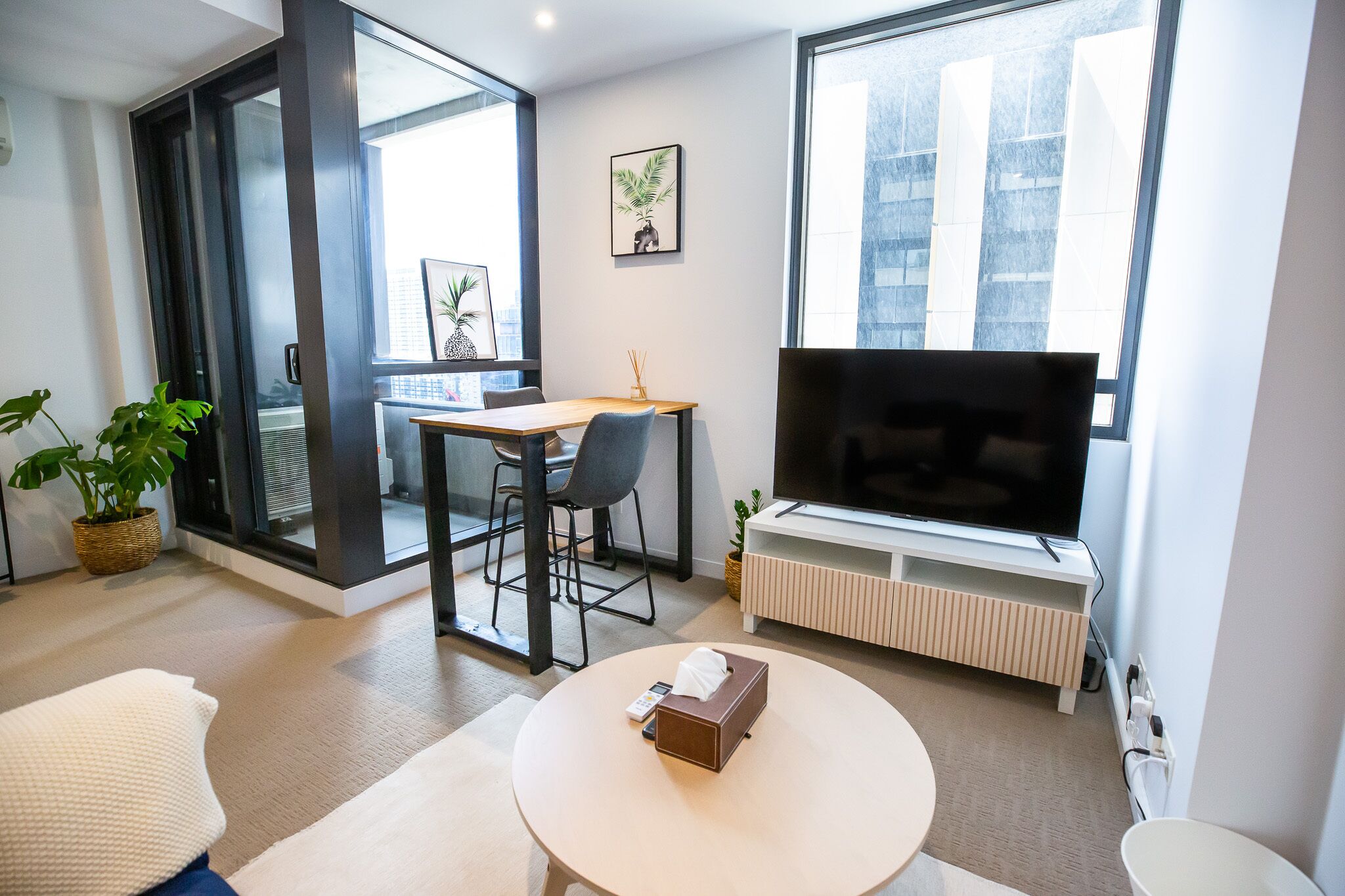Un salon moderne comprenant un canapé, une table basse ronde, un téléviseur et un coin repas avec une table et des chaises.