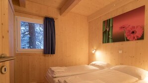 A wooden room with a bed, a window with a curtain, and a wall-mounted light. - #27 mit IR-Sauna und Sprudelbad Innen by Interhome (Turracher Höhe)