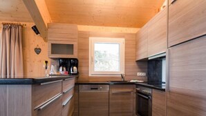 A compact kitchen with wooden cabinets, a built-in microwave, and a window above the sink. - #27 mit IR-Sauna und Sprudelbad Innen by Interhome (Turracher Höhe)