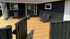 Une terrasse dotée de mobilier d’extérieur, d’une porte-fenêtre coulissante et d’une cheminée.