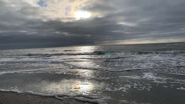 Une plage avec des vagues et un ciel nuageux.