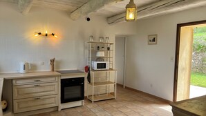 Una cocina con armarios blancos, un horno negro, un microondas y un farol colgante.