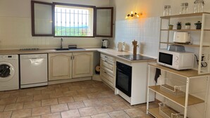 Una cocina compacta con lavadora, microondas y tostadora sobre la encimera.