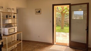 Una habitación con techo de madera, un microondas blanco sobre una repisa, un cuadro en la pared y una puerta que da al exterior.