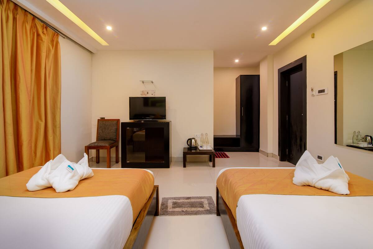 A hotel room with two beds, a TV, a desk, and a chair.