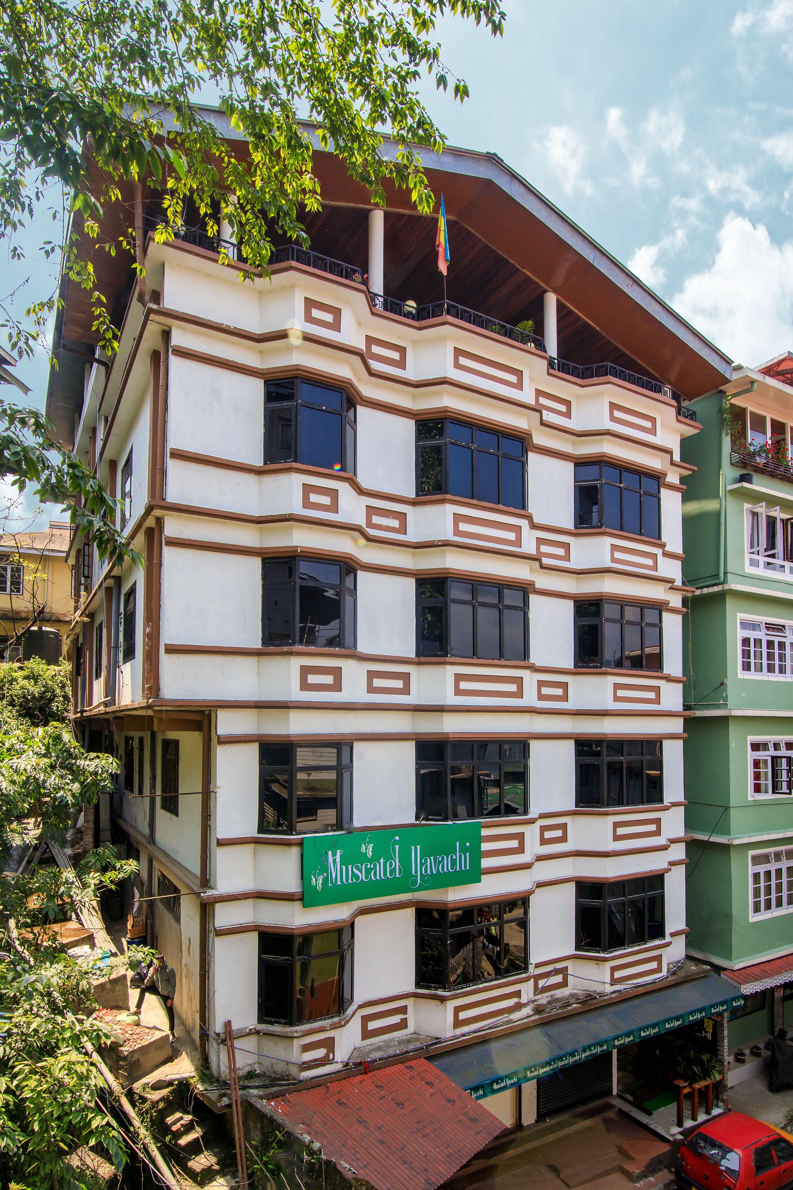 Un edificio de varios pisos con un letrero verde que dice "Muscatel Yavachi".