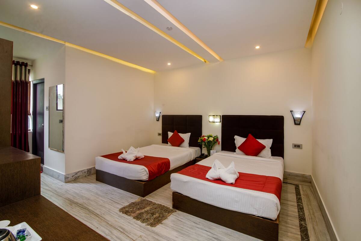A hotel room with two beds, a desk, and a bathroom visible through an open door.