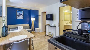 A compact living space with a dining area, kitchenette, and a TV mounted on the wall. - Cozy 2-Room Apartment in Cauterets Center - Sleeps 2-4, Well-Equipped Kitchen, Near Ski Lifts (Cauterets)