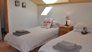Ein Schlafzimmer mit zwei Betten, einem Oberlicht und einem Nachttisch mit Lampe.