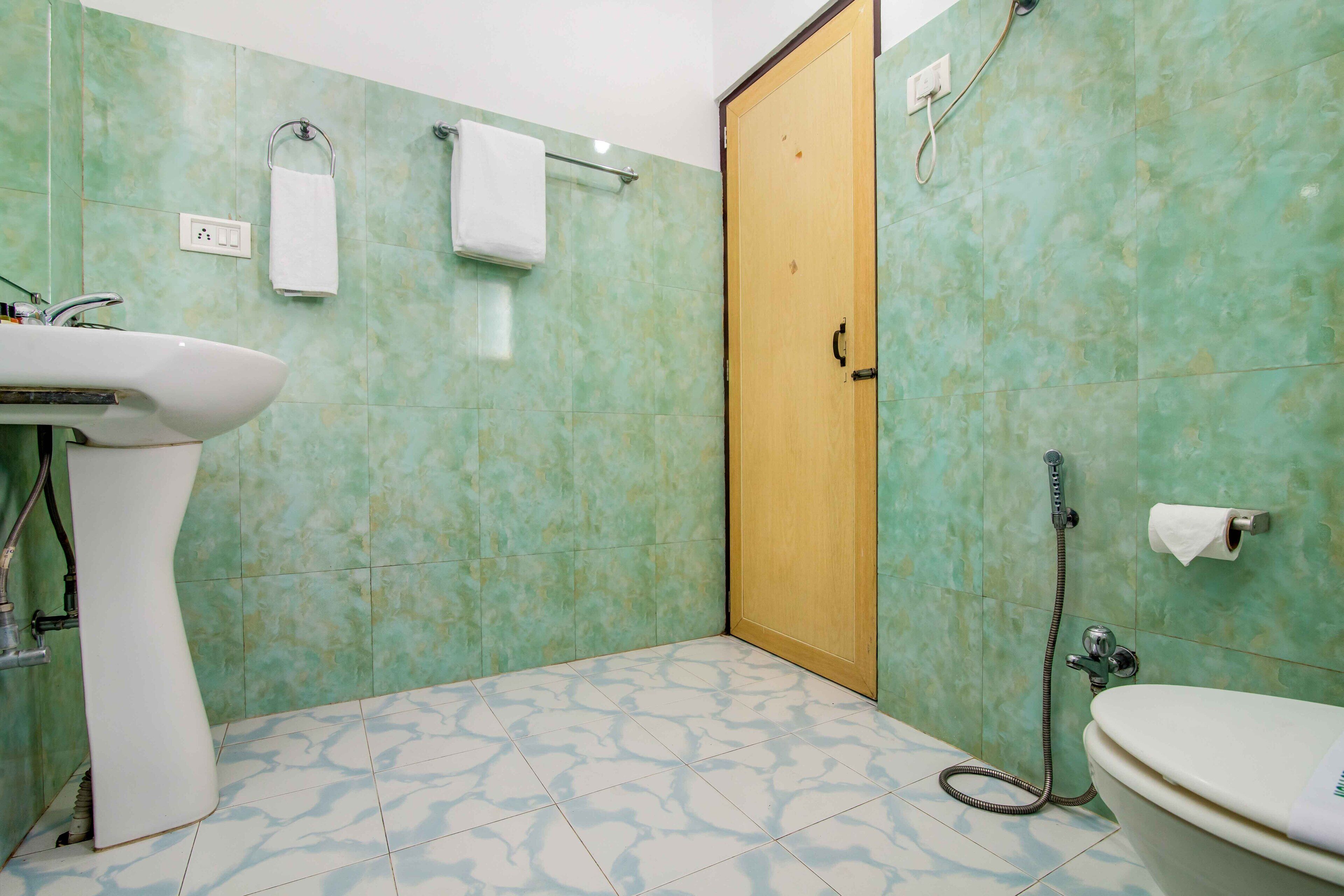 Een badkamer met een wastafel, toilet, douche en een deur.