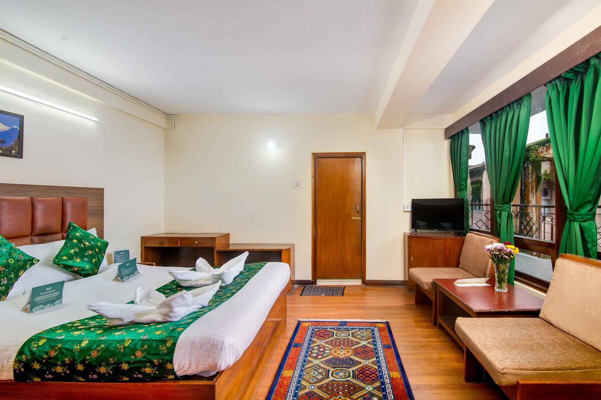 Una habitación de hotel con cama, sofá, una mesita y televisor.