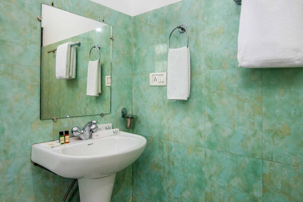 Un baño con lavamanos, espejo y dos toallas colgadas en barras.