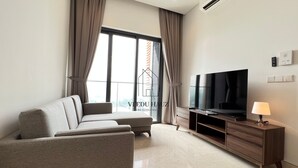 Un salon moderne avec un canapé, un téléviseur à écran plat, une lampe et un ventilateur de plafond.