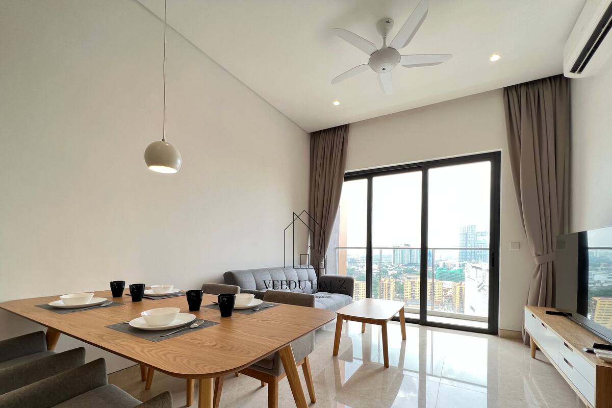 A modern living room with a dining area, a sofa, a TV, and a large window with a city view.