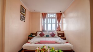 Una camera da letto ordinata con un letto grande, un comodino, una abat-jour e una finestra con tende.