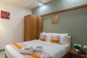 Una cama bien hecha con una colcha estampada y una toalla doblada al lado.