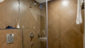 Et moderne badeværelse med en brusekabine i glas, et hvidt toilet og en håndklæderække.