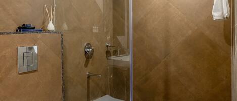 Une salle de bain moderne avec une douche à parois de verre, des toilettes blanches et un porte-serviettes.